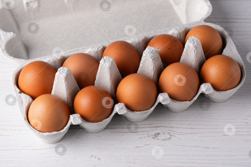 Скачать Фермерское сырое свежее яйцо в упаковке на белом деревянном столе фотосток Ozero