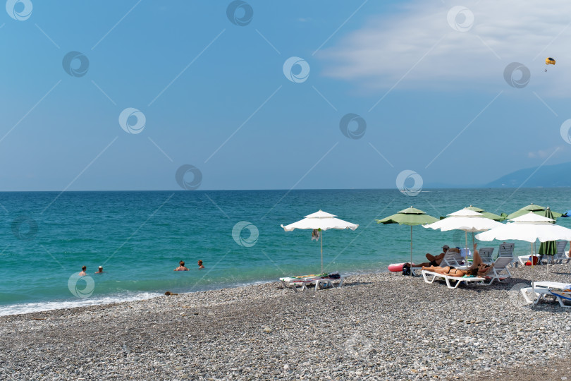 Скачать Лазурное море, пляж, отдыхающие, загорающие на берегу. Абхазия, город Гагра - 18 августа 2023 года фотосток Ozero