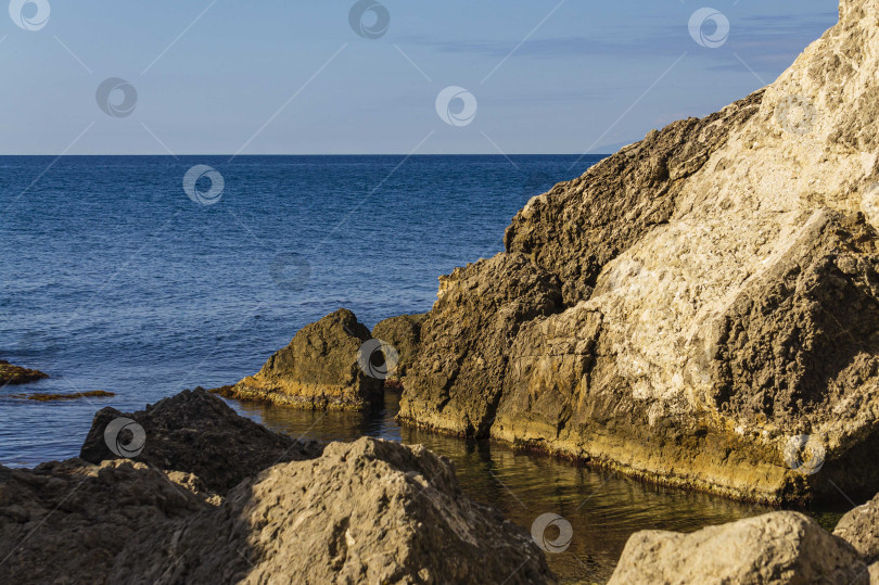 Скачать Скалистый берег Черного моря. Мыс Алчак. Дикая природа вблизи древнего города, построенного генуэзцами. Бархатный сезон в Судаке в Крыму. Огромные камни и валуны в море и на фоне моря. Крупный план. фотосток Ozero