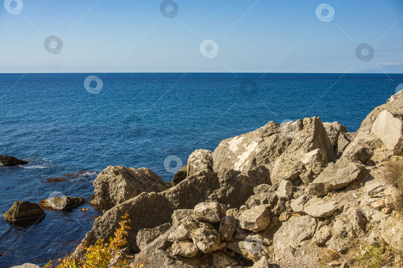 Скачать Скалистый берег Черного моря. Мыс Алчак. Дикая природа вблизи древнего города, построенного генуэзцами. Бархатный сезон в Судаке в Крыму. Огромные камни и валуны в море и на фоне моря. Крупный план. фотосток Ozero