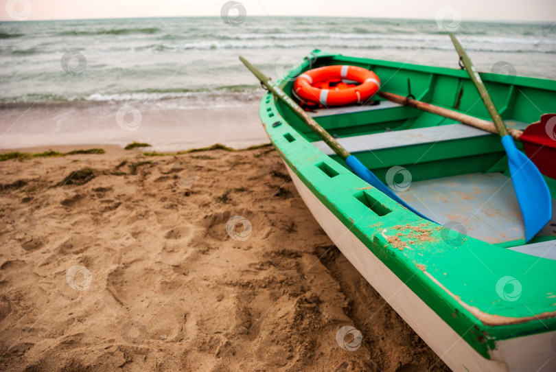 Скачать Лодка с грузами и спасательным кругом стоит на песчаном морском берегу. фотосток Ozero