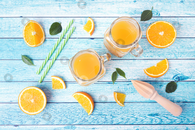 Скачать Апельсиновый сок в стеклянных банках и свежие апельсины на синем фоне. фотосток Ozero