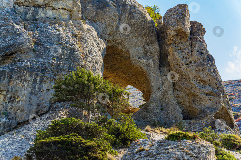 Скачать Мыс Алчак на южном побережье Крыма на окраине курортного города Судак. Потрясающий вид на большую гору с гротом Эоловой арфы на тропе Алчак-Кая. Крупный план огромных камней и природных валунов фотосток Ozero