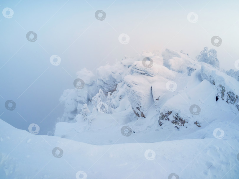 Скачать Красивый снежный и скалистый горный пейзаж с застывшим туманом. фотосток Ozero