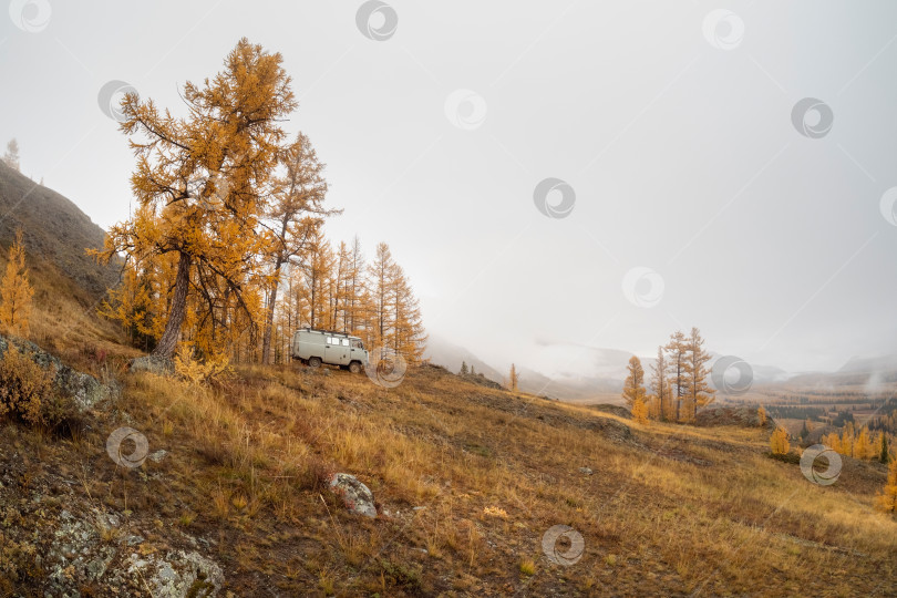 Скачать Путешествие по осенним горам на машине. Машина на лесной тропе, вид сбоку. фотосток Ozero