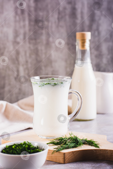 Скачать Домашний йогуртовый напиток Айран с укропом в стакане на столе вертикальный вид фотосток Ozero