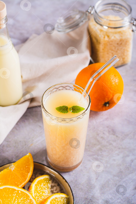 Скачать Диетический апельсиновый смузи с рисовым молоком в стакане на столе вертикальный вид фотосток Ozero