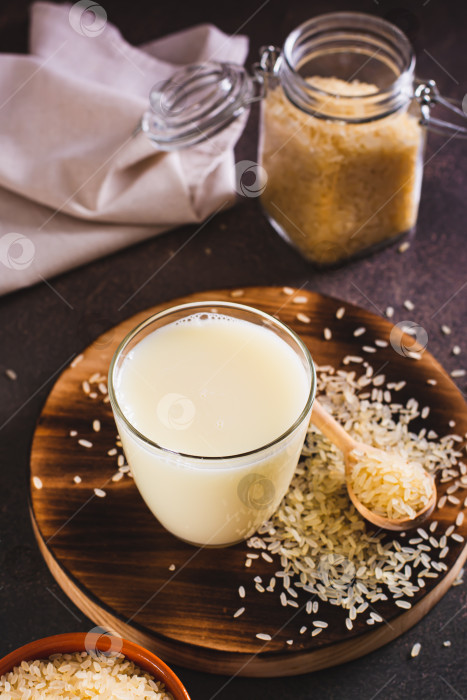 Скачать Альтернативное полезное рисовое молоко в стакане и рисовые хлопья на столе вид по вертикали фотосток Ozero
