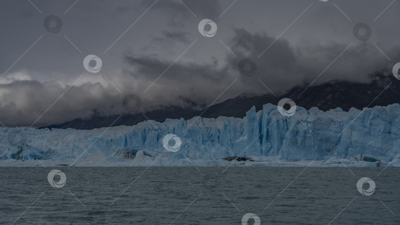 Скачать Стена голубого льда с трещинами и острыми пиками возвышается в ледниковом озере. фотосток Ozero