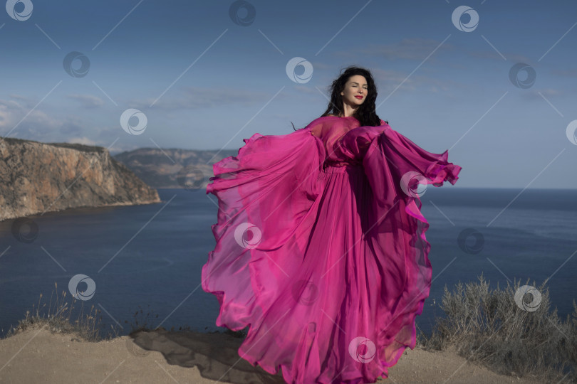 Скачать Красивая девушка в длинном розовом платье стоит на краю белых скал у церкви Святой Марии Магдалины на острове Мальта фотосток Ozero