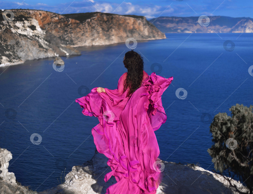 Скачать Красивая девушка в длинном розовом платье стоит на краю белых скал у церкви Святой Марии Магдалины на острове Мальта фотосток Ozero