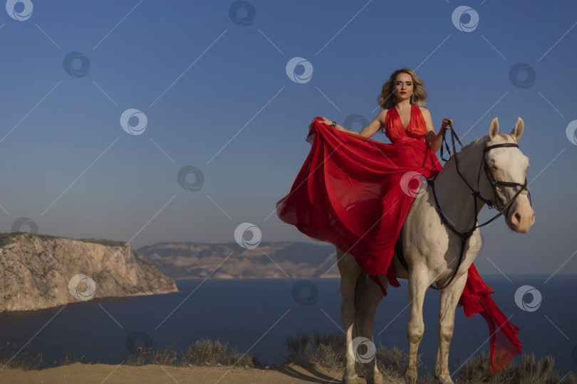 Скачать Красивая девушка в длинном красном платье обнимает лошадь на пляже фотосток Ozero