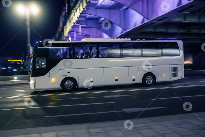 Скачать Туристический автобус едет ночью по освещенной дороге фотосток Ozero