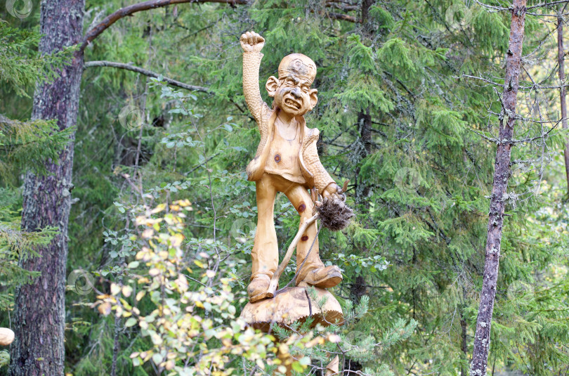 Скачать Гном вырезанный из дерева стоит на грибе на фоне леса фотосток Ozero
