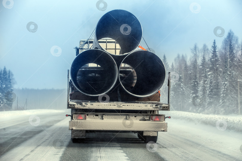 Скачать грузовик перевозит трубы большого диаметра для газопровода по зимней дороге. фотосток Ozero