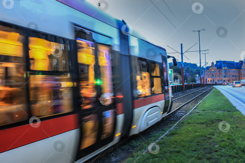 Скачать трамвай движется по городской улице вечером в сумерках. фотосток Ozero