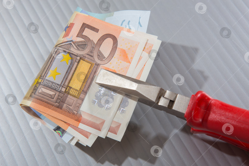 Скачать банкноты евро, зажатые плоскогубцами фотосток Ozero