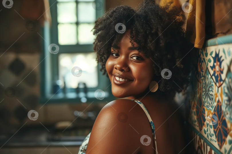 Скачать Портрет позитивной афроамериканки, пухленькой молодой женщины в платье, смотрящей в камеру, стоя на кухне у себя дома, индивидуальность фотосток Ozero