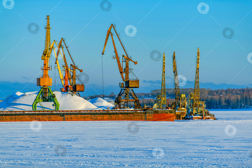 Скачать Замерзший морской и речной порт с грузовыми кранами. Вид Арктики. Проблемы навигации зимой. Морская инфраструктура на Крайнем Севере. Зимний промышленный пейзаж. фотосток Ozero