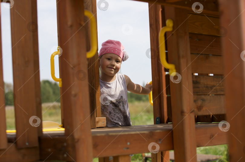 Скачать Девочка, ребёнок стоит на детском городке в парке, играют в игры фотосток Ozero