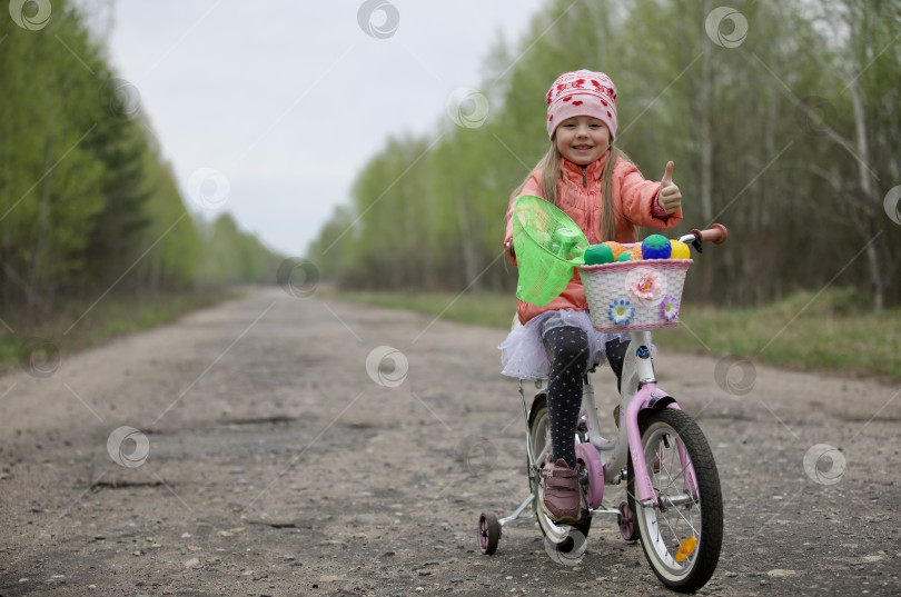 Скачать Девочка, ребёнок весело катается на трёх колёсном велосипеде по доро фотосток Ozero