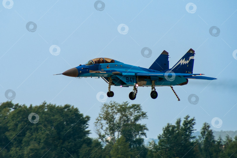 Скачать Российский палубный многоцелевой истребитель МиГ-29К (НАТО - Fulcrum-D) заходит на посадку над деревьями. Выпущены шасси и посадочный крюк. Размытый фон. фотосток Ozero