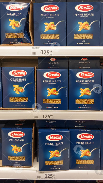 Скачать Гипермаркет Ашан в торговом центре "Сказка". Коробки с пастой Barilla Penne Rigate от зарубежных производителей лежат на полках. Крупный план. Продается за рубли. фотосток Ozero