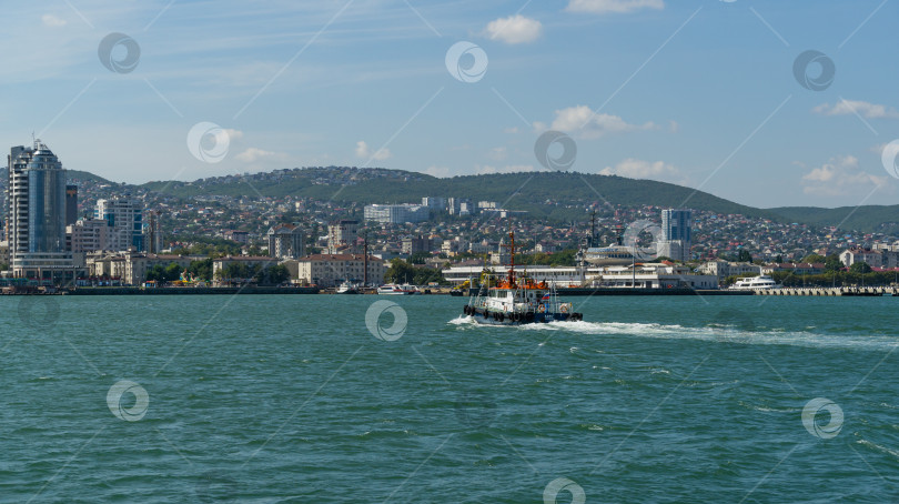 Скачать Морской лоцман "Адис" плывет по бирюзовой воде вдоль Цемесского залива. Крупный план белого рабочего катера "Адис" на фоне Новороссийского морского торгового порта.  Новороссийск, Россия - 15 сентября 2021 г. фотосток Ozero