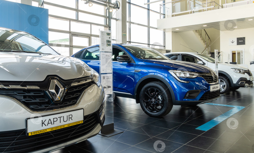 Скачать Вид справа крупным планом на белый внедорожник Renault Kaptur в ряду автомобилей Renault в демонстрационном зале дилерского центра Renault. Мега Адыгея. фотосток Ozero