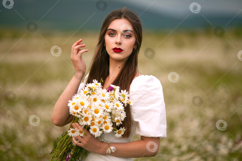 Скачать Женщина в поле с цветами. Красивая девушка в поле с маргаритками. фотосток Ozero