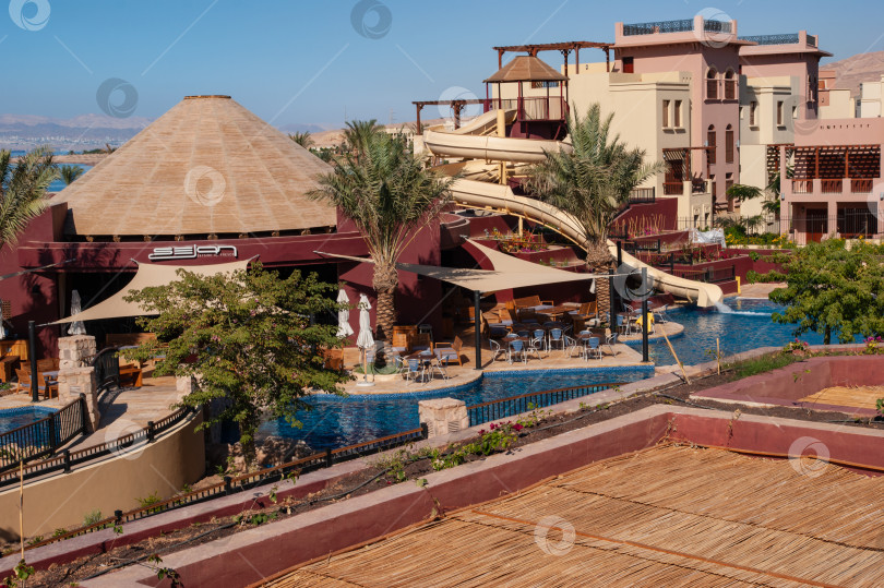 Скачать Отель Movenpick Resort and SPA Tala Bay Aqaba 5 звезд на берегу Красного моря в Иордании. Территория отеля с множеством бассейнов, окруженных пальмами. Акаба, Иордания - 06 декабря 2009 г. фотосток Ozero