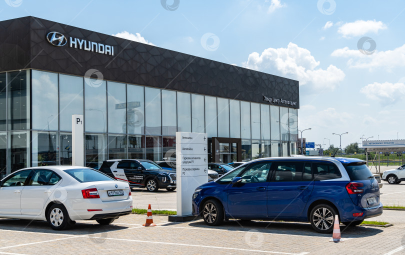 Скачать Дилерский центр Hyundai с автомобилями снаружи. Логотип Hyundai и название производителя автомобилей на фасаде здания в Мега Адыгея. Краснодар, Россия - 04 августа 2022 г. фотосток Ozero