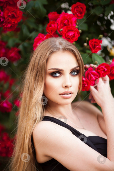 Скачать Красивая модная женщина с красным макияжем губ позирует на открытом воздухе, в цветущем розовом саду. Копия, пустое место для текста фотосток Ozero