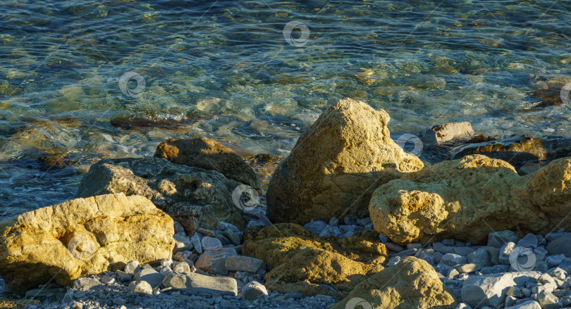 Скачать Большие желтые скалы на фоне синего моря на закате. Морские камни и утесы разных размеров и фактуры на пляже и под водой побережья Черного моря в качестве фона природы. фотосток Ozero