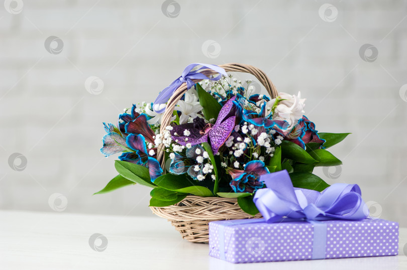 Скачать Преподнесите рядом с композицией из орхидей, голубых альстромерий, лилий и в соломенной корзинке фотосток Ozero