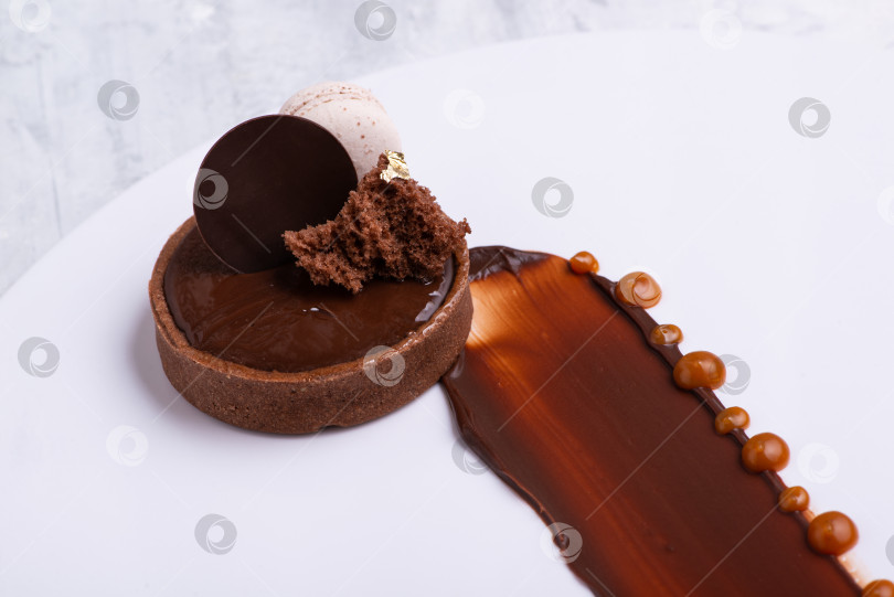 Скачать Крупным планом показан восхитительный шоколадный десерт с макарунами, поданный на белой тарелке фотосток Ozero