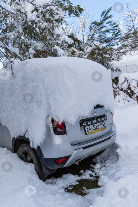 Скачать Автомобиль Renault Duster припаркован под огромным сугробом. Крупный план. Сугробы на крыше автомобиля после сильного ночного снегопада. Экстремальные сугробы на юге России. фотосток Ozero