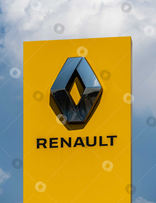 Скачать Логотип автопроизводителя Renault на желтом вертикальном пилоне. Пилон с логотипом между шоссе и автостоянкой перед сервисным центром Renault в Адыгее. фотосток Ozero