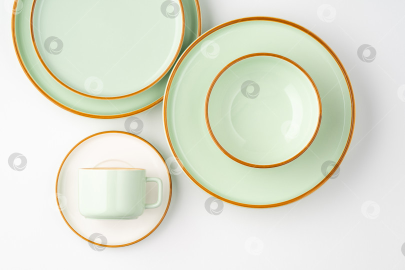 Скачать Набор белой и пастельно-зеленой керамической посуды с оранжевыми контурами. Вид сверху фотосток Ozero