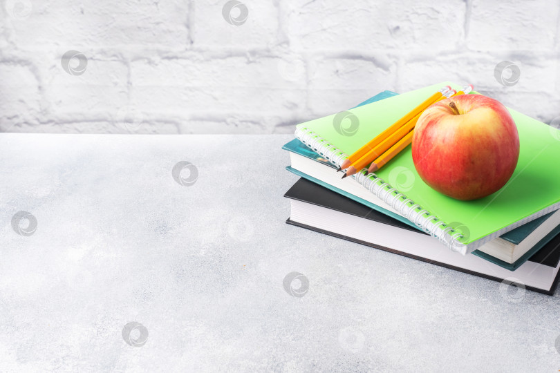 Скачать Свежее красное яблоко на стопке книг и тетрадей. Концепция перекуса на школьный завтрак. Место для копирования, фотосток Ozero