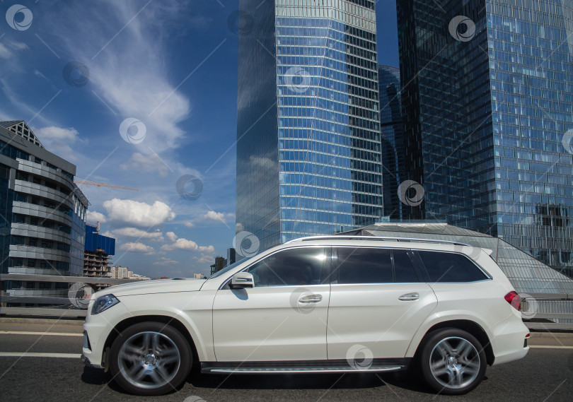 Скачать Внедорожник движется по мосту мимо небоскребов фотосток Ozero