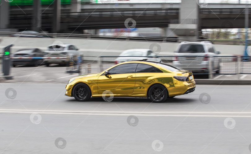 Скачать Золотистый автомобиль едет по городской улице. фотосток Ozero