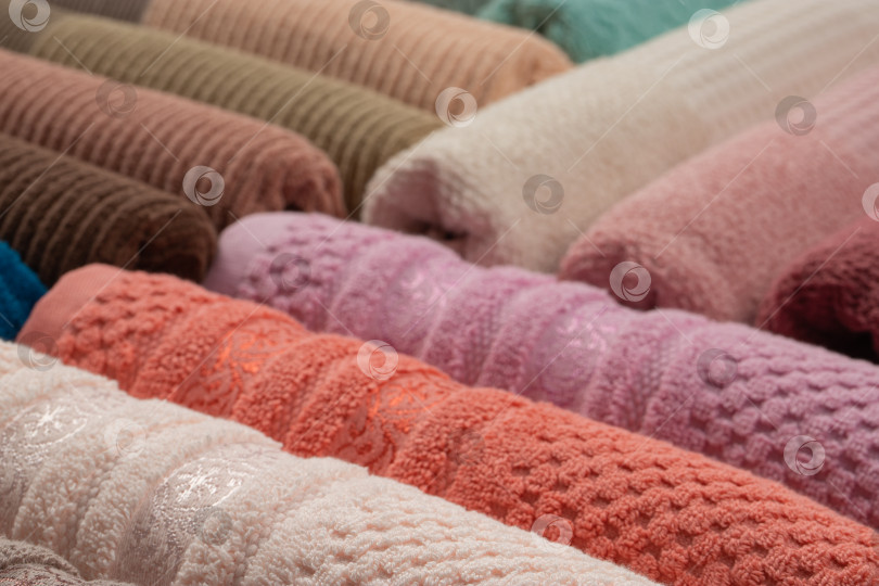 Скачать разноцветные махровые полотенца, свернутые в рулон и сложенные стопкой на столе фотосток Ozero