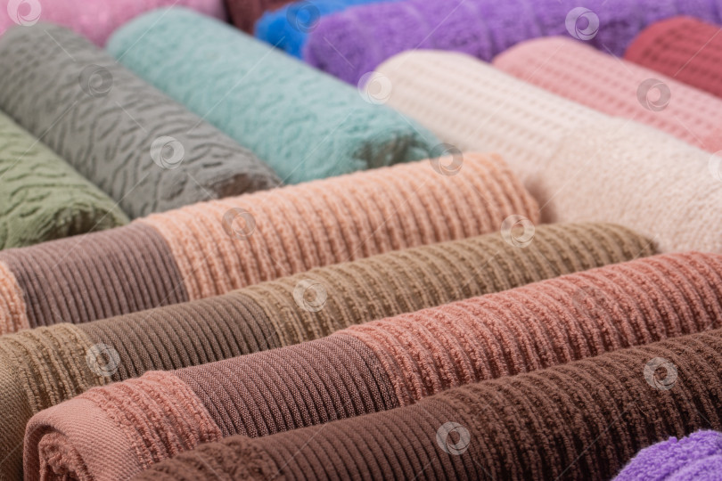 Скачать разноцветные махровые полотенца, свернутые в рулон и сложенные стопкой на столе фотосток Ozero