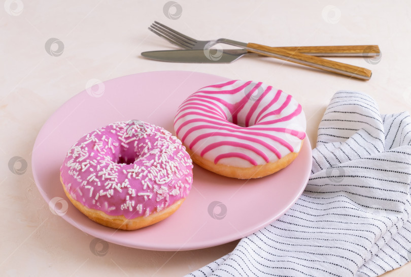 Скачать Два пончика в сахарной глазури лежат на розовой керамической тарелке фотосток Ozero