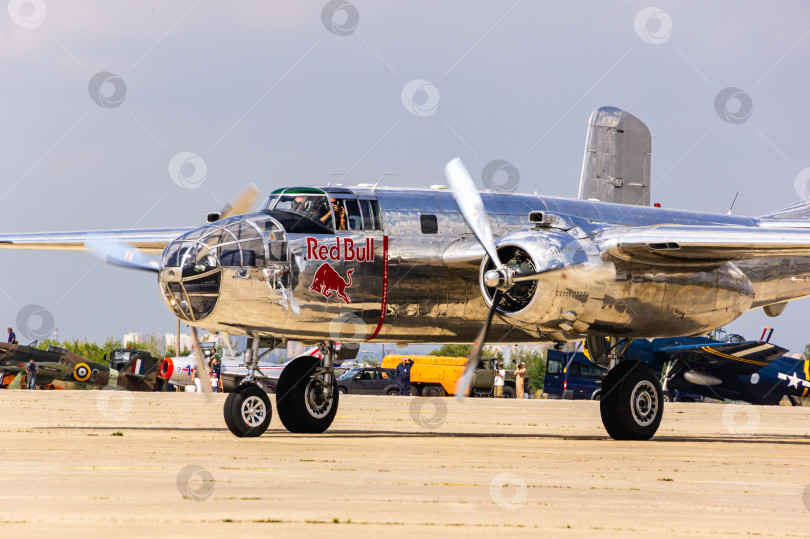 Скачать Американский двухмоторный бомбардировщик North American B-25 "Митчелл" времен Второй мировой войны выруливает со стоянки на взлетно-посадочную полосу для взлета. Red Bull. 100 лет Военно-воздушным силам России. фотосток Ozero