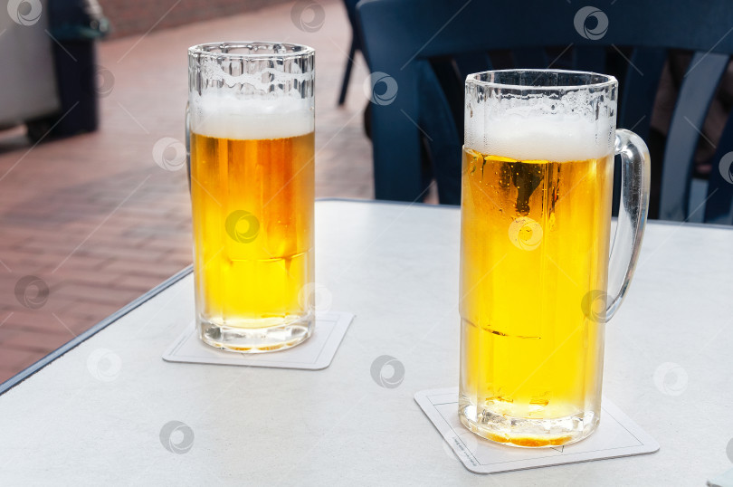 Скачать Бокалы с холодным пивом на белом столе фотосток Ozero