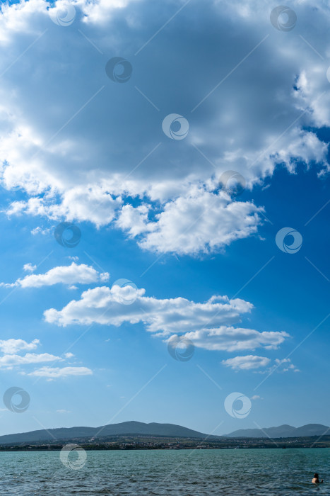 Скачать Белые красивые облака на бескрайних просторах Черного моря. Облака на фоне Кавказских гор. Изумрудная морская вода. Облака отражаются в морской воде. фотосток Ozero