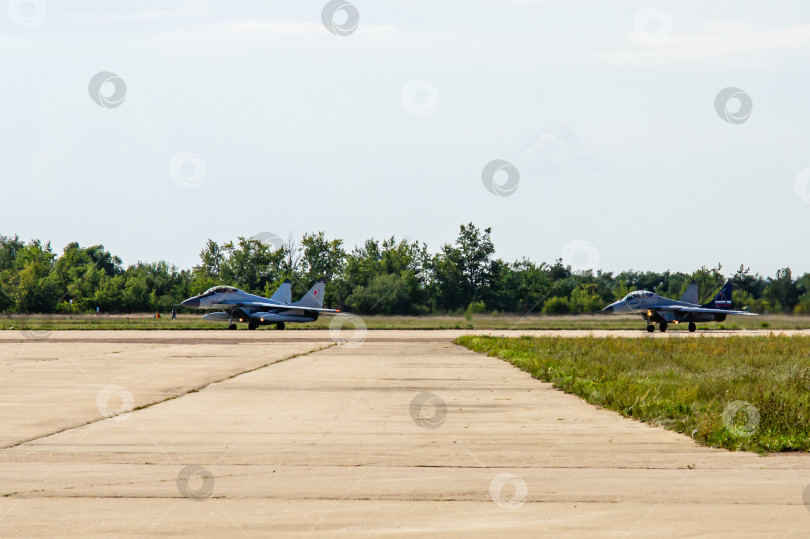 Скачать Российский многоцелевой истребитель четвертого поколения МиГ-29М2 с внешними топливными баками и истребитель МиГ-35 поколения "четыре плюс плюс" (НАТО-Fulcrum) на взлетно-посадочной полосе перед взлетом. фотосток Ozero