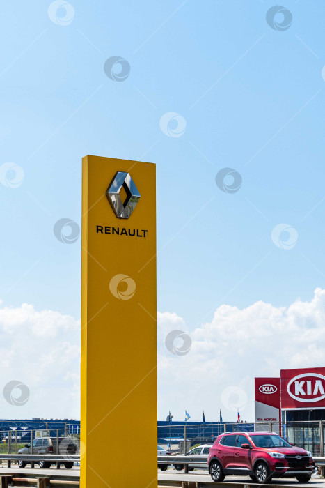 Скачать Логотип автопроизводителя Renault на желтом вертикальном пилоне. Пилон с логотипом между шоссе и автостоянкой перед сервисным центром Renault в Адыгее. фотосток Ozero